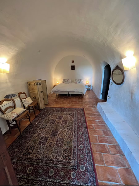 From the living area, you wind down the stairs into the lower level of the house. Along the way, you pass the original stone wall of the house.  Here you enter Bedroom 3.  This is the original caved room of the house dating back to the birth of the village.